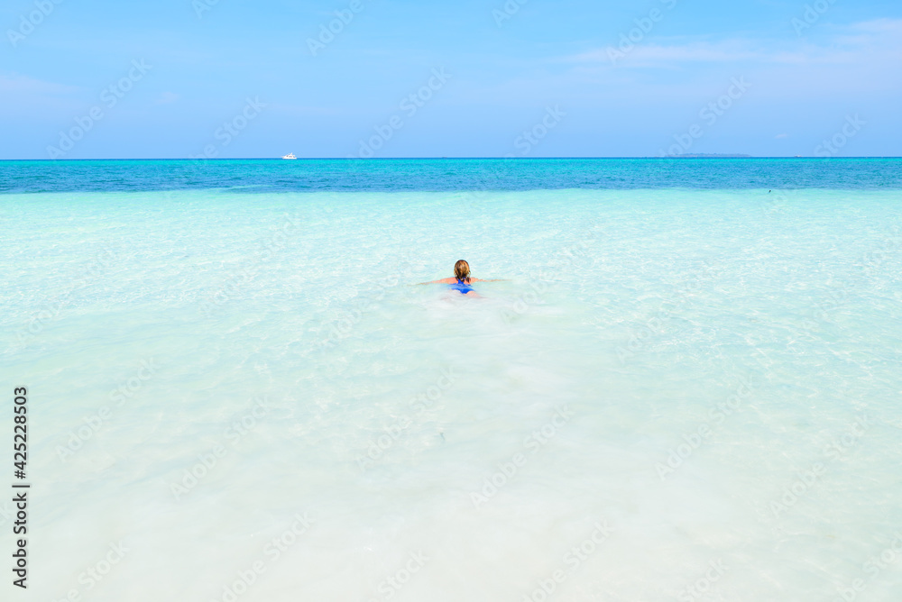 Woman swimming in caribbean sea turquoise transparent water. Tropical beach in the Kei Islands Moluccas, summer tourist destination in Indonesia. Woman swimming in caribbean sea turquoise transparent water. Tropical beach in the Kei Islands Moluccas, summer tourist destination in Indonesia.