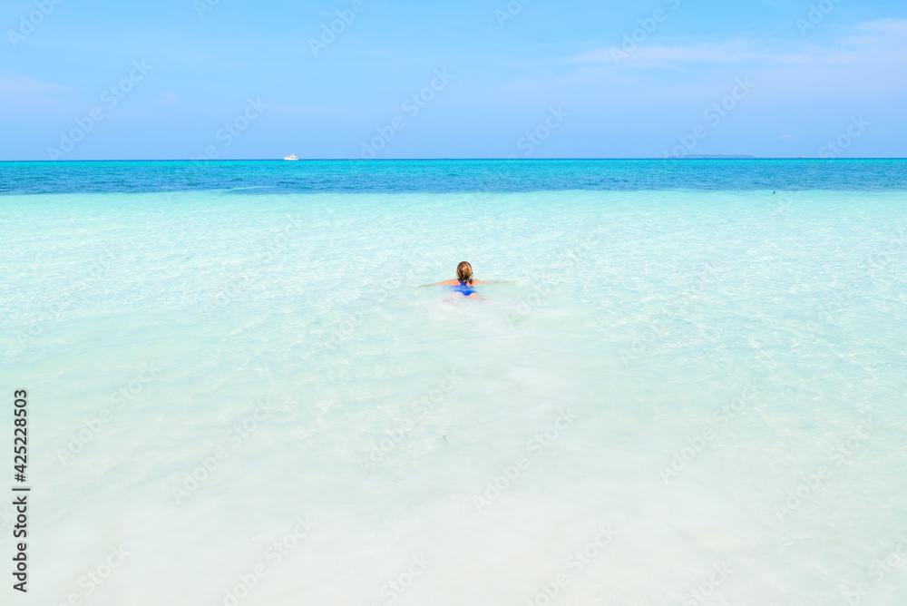 Woman swimming in caribbean sea turquoise transparent water. Tropical beach in the Kei Islands Moluccas, summer tourist destination in Indonesia.