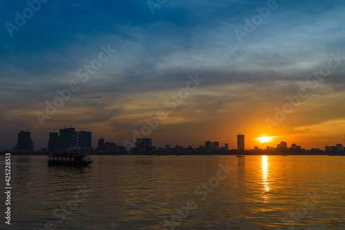 Phnom Penh skyline at sunset capital city of Cambodia kingdom, panorama silhouette view from Mekong river, travel destination, dramatic sky