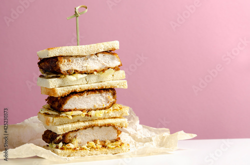 Katsu sandos japanese sandwich with chicken or pork chop, cabbage and tonkatsu sauce isolated on pink background. photo