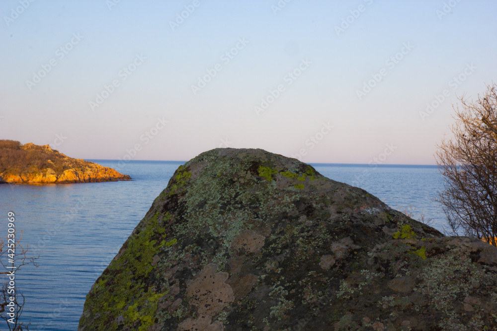Sunset in the bay among the rocks overlooking the calm sea Sunset in the bay among the rocks overlooking the calm sea