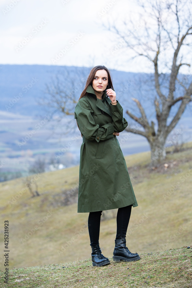 Image of young beautiful woman wearing rain jacket in cold weather. Thinker european girl in spring nature. Image of young beautiful woman wearing rain jacket in cold weather. Thinker european girl in spring nature.