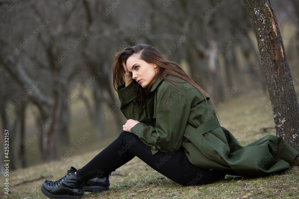 Image of young beautiful woman wearing rain jacket in cold weather. Thinker european girl in spring nature. Image of young beautiful woman wearing rain jacket in cold weather. Thinker european girl in spring nature.