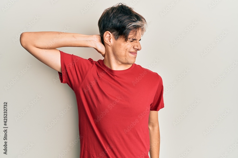 Young hispanic man wearing casual clothes suffering of neck ache injury, touching neck with hand, muscular pain Young hispanic man wearing casual clothes suffering of neck ache injury, touching neck with hand, muscular pain