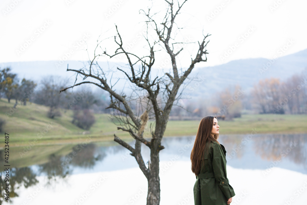 Image of young beautiful woman wearing rain jacket in cold weather. Thinker european girl in spring nature. Image of young beautiful woman wearing rain jacket in cold weather. Thinker european girl in spring nature.