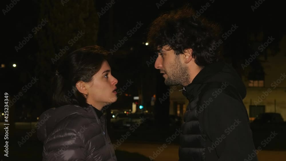 night discussion - young couple on the street at night argues animatedly night discussion - young couple on the street at night argues animatedly