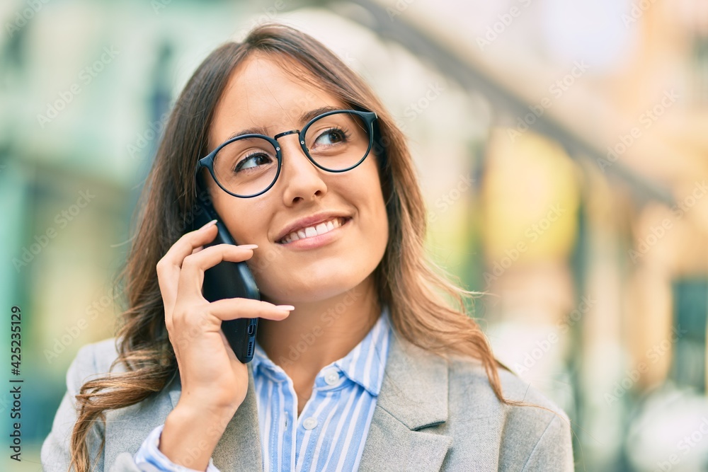 Young hispanic businesswoman smiling happy talking on the smartphone at the city.