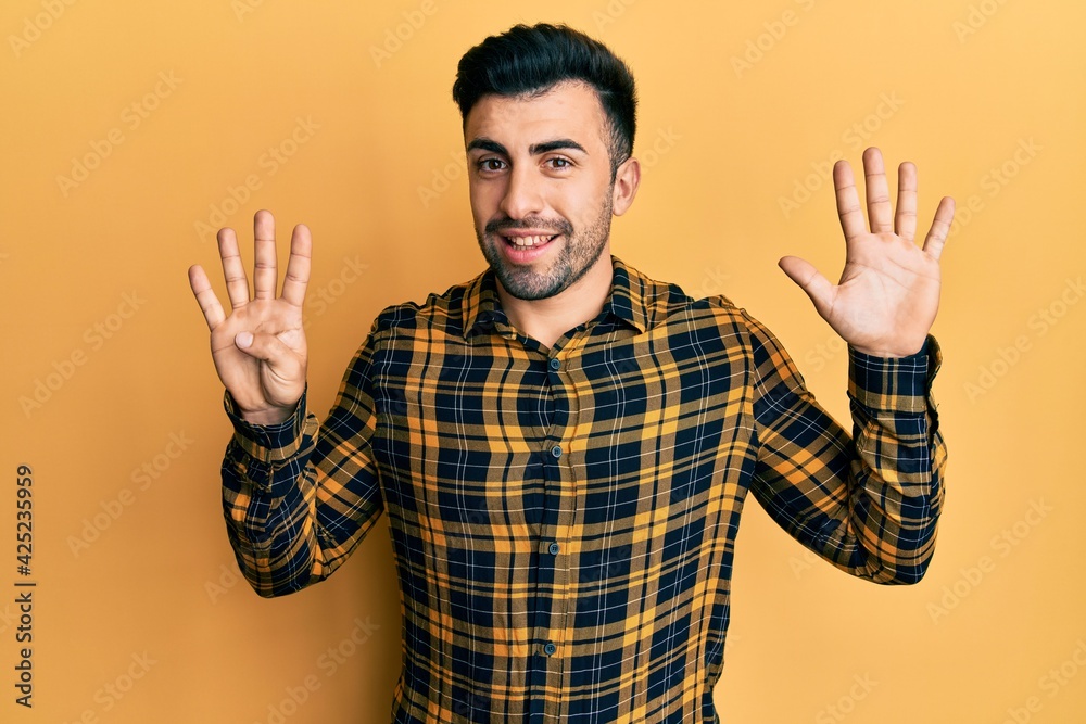 Naklejka premium Young hispanic man wearing casual clothes showing and pointing up with fingers number nine while smiling confident and happy.