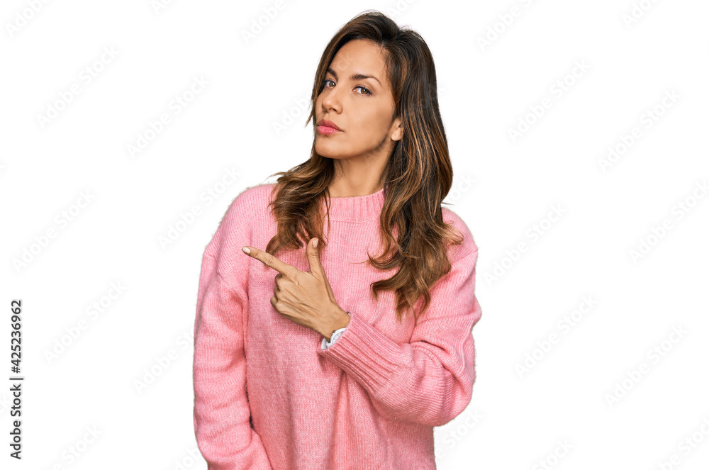 Young hispanic woman wearing casual clothes pointing with hand finger to the side showing advertisement, serious and calm face