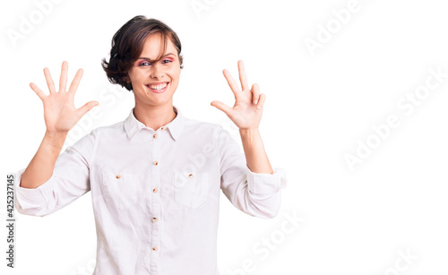 Beautiful young woman with short hair wearing elegant white shirt showing and pointing up with fingers number eight while smiling confident and happy. © Krakenimages.com