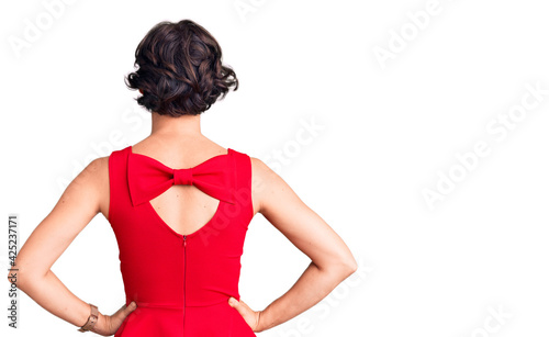 Beautiful young woman with short hair wearing casual style with sleeveless shirt standing backwards looking away with arms on body photo