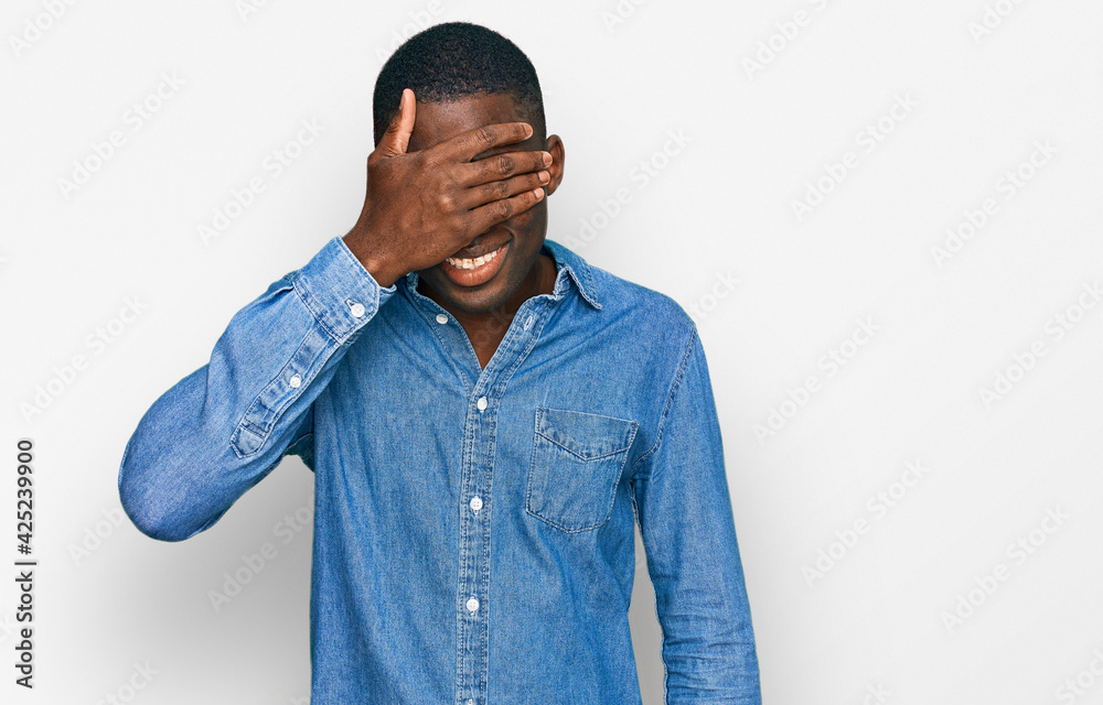 Young african american man wearing casual clothes smiling and laughing with hand on face covering eyes for surprise. blind concept. Young african american man wearing casual clothes smiling and laughing with hand on face covering eyes for surprise. blind concept.