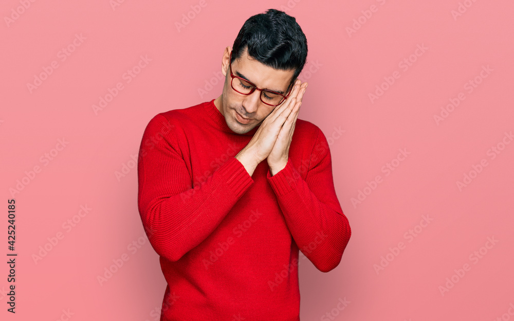 Handsome hispanic man wearing casual clothes and glasses sleeping tired dreaming and posing with hands together while smiling with closed eyes. Handsome hispanic man wearing casual clothes and glasses sleeping tired dreaming and posing with hands together while smiling with closed eyes.