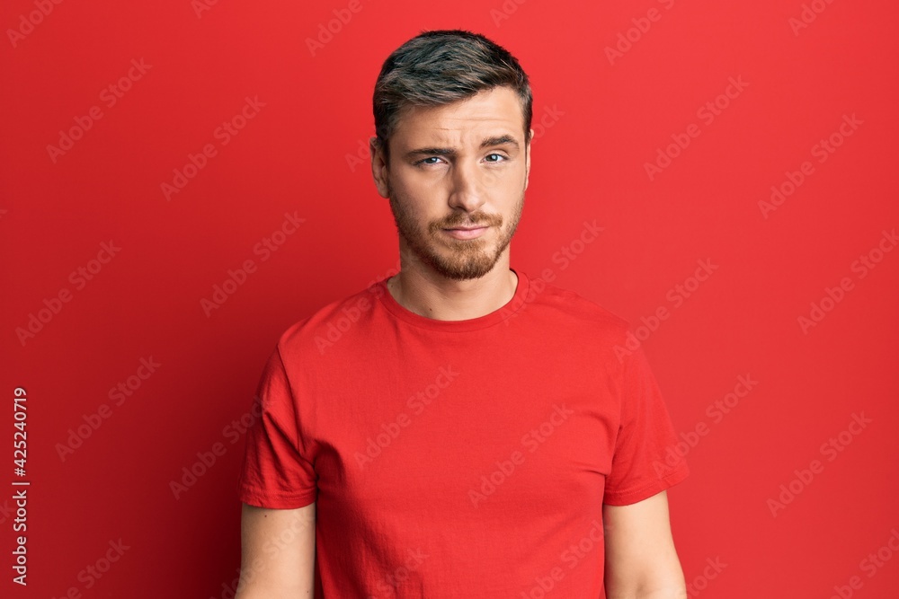Handsome caucasian man wearing casual red tshirt skeptic and nervous, frowning upset because of problem. negative person.