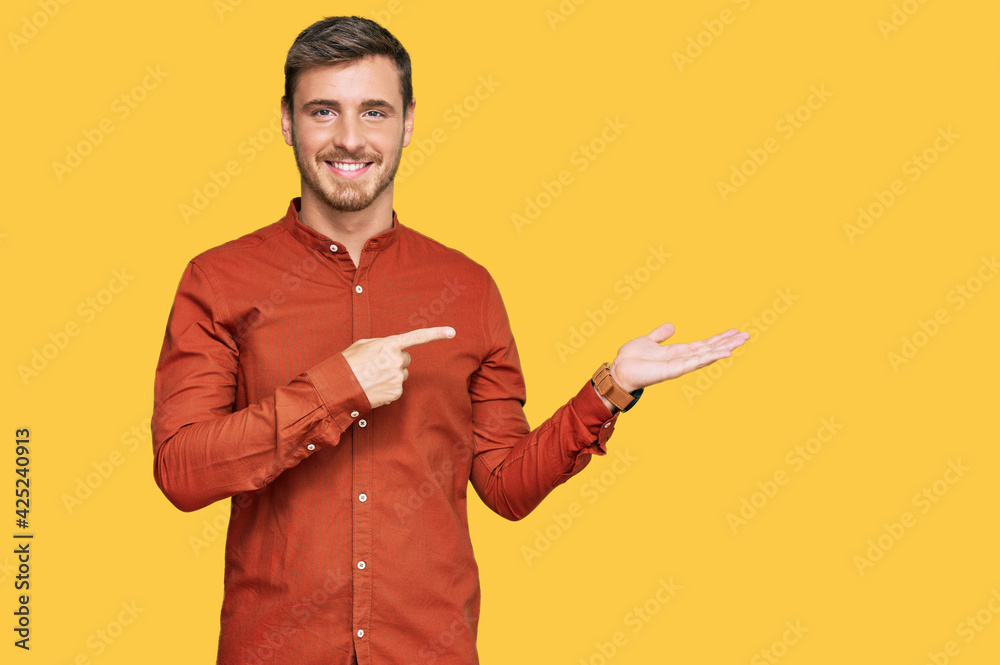 Handsome caucasian man wearing casual clothes amazed and smiling to the camera while presenting with hand and pointing with finger. Handsome caucasian man wearing casual clothes amazed and smiling to the camera while presenting with hand and pointing with finger.
