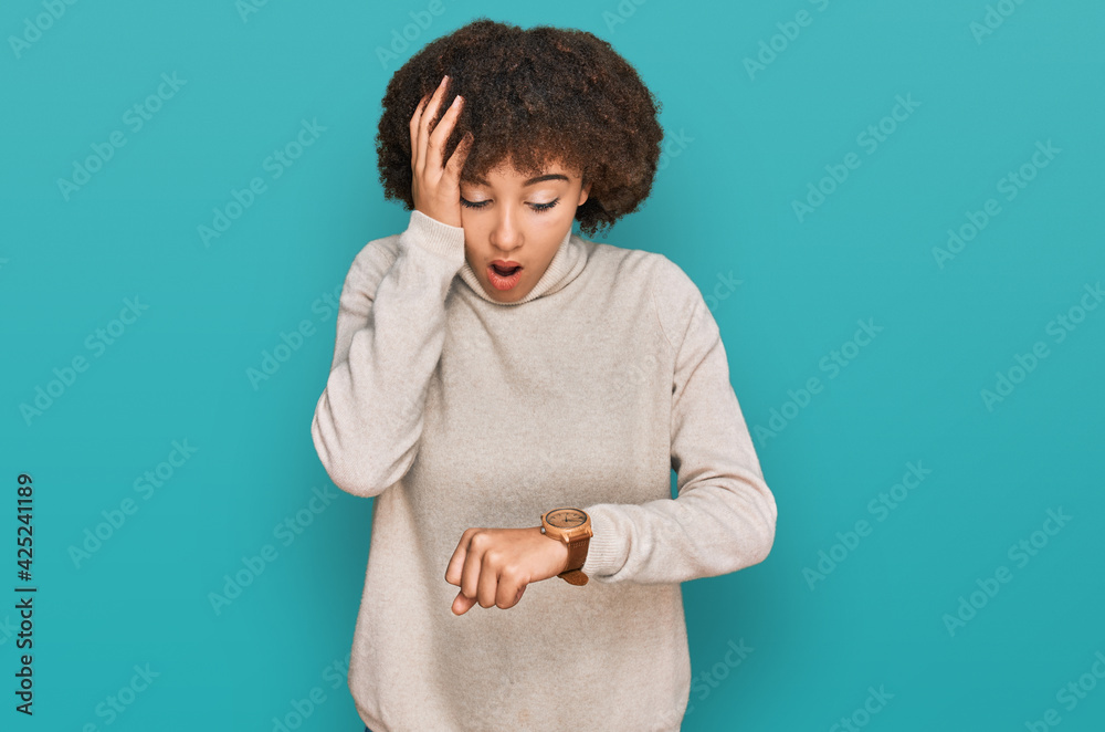 Young hispanic girl wearing wool winter sweater looking at the watch time worried, afraid of getting late Young hispanic girl wearing wool winter sweater looking at the watch time worried, afraid of getting late