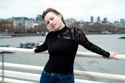 Atractive young woman posing in Waterloo bridge in London in a windy and cloudy day.