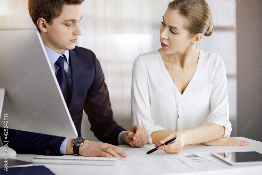 Business people discussing something while sitting in sunny office. Focus at businesswoman while talking to her male colleague Business people discussing something while sitting in sunny office. Focus at businesswoman while talking to her male colleague
