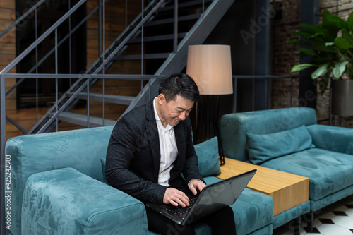 Successful Asian businessman, in a black business suit, works on a laptop, relaxes in a restaurant or hotel, and in a stylish office explains a new business strategy via video link © Liubomir