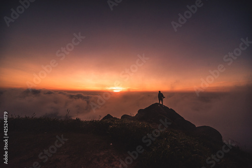 silhouette of a person on top of the mountain above the clouds