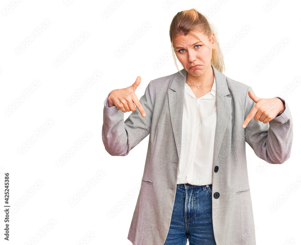 Young beautiful blonde woman wearing elegant jacket pointing down looking sad and upset, indicating direction with fingers, unhappy and depressed. Young beautiful blonde woman wearing elegant jacket pointing down looking sad and upset, indicating direction with fingers, unhappy and depressed.