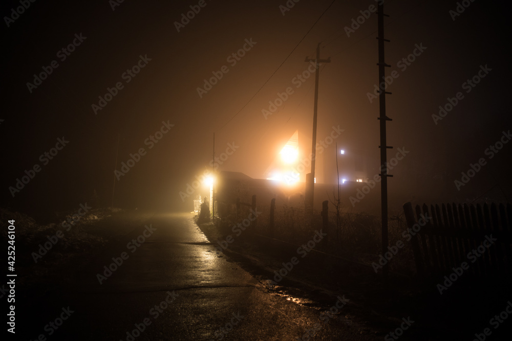 Night street country road with buildings and fences covered in fog lamp . Or Mysterious night in Azerbaijan mountain village