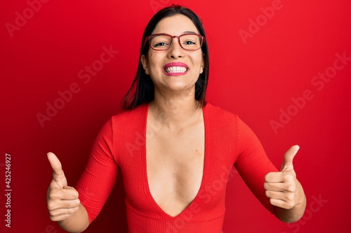 Young latin woman wearing casual clothes and glasses success sign doing positive gesture with hand, thumbs up smiling and happy. cheerful expression and winner gesture.