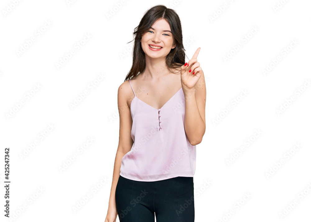 Young beautiful caucasian girl wearing casual clothes showing and pointing up with finger number one while smiling confident and happy. Young beautiful caucasian girl wearing casual clothes showing and pointing up with finger number one while smiling confident and happy.