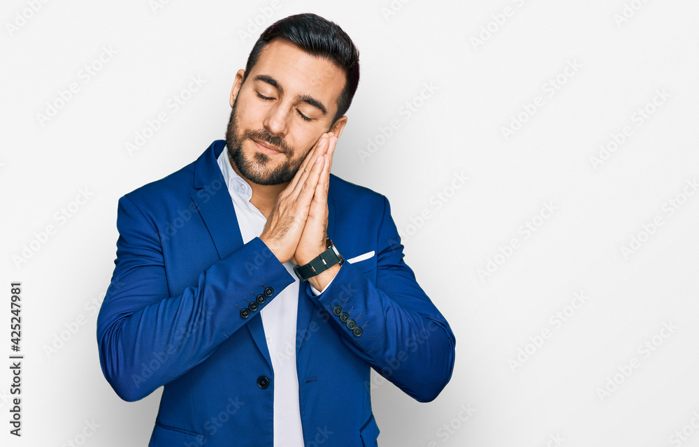 Young hispanic man wearing business jacket sleeping tired dreaming and posing with hands together while smiling with closed eyes. Young hispanic man wearing business jacket sleeping tired dreaming and posing with hands together while smiling with closed eyes.