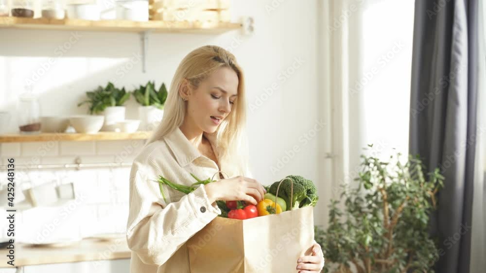 close-up of a woman holding a large bag of fresh vegetables at home in the kitchen. healthy lifestyle, diet, cooking, veganism