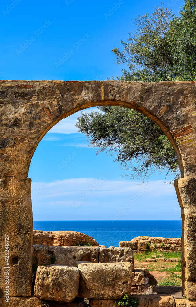 The beautiful Mediterranean sea through Roman ruins arch