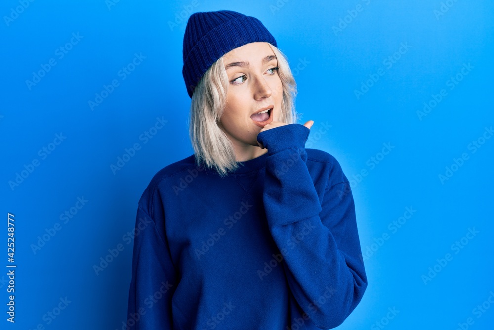 Young blonde girl wearing casual clothes smiling with happy face looking and pointing to the side with thumb up. Young blonde girl wearing casual clothes smiling with happy face looking and pointing to the side with thumb up.