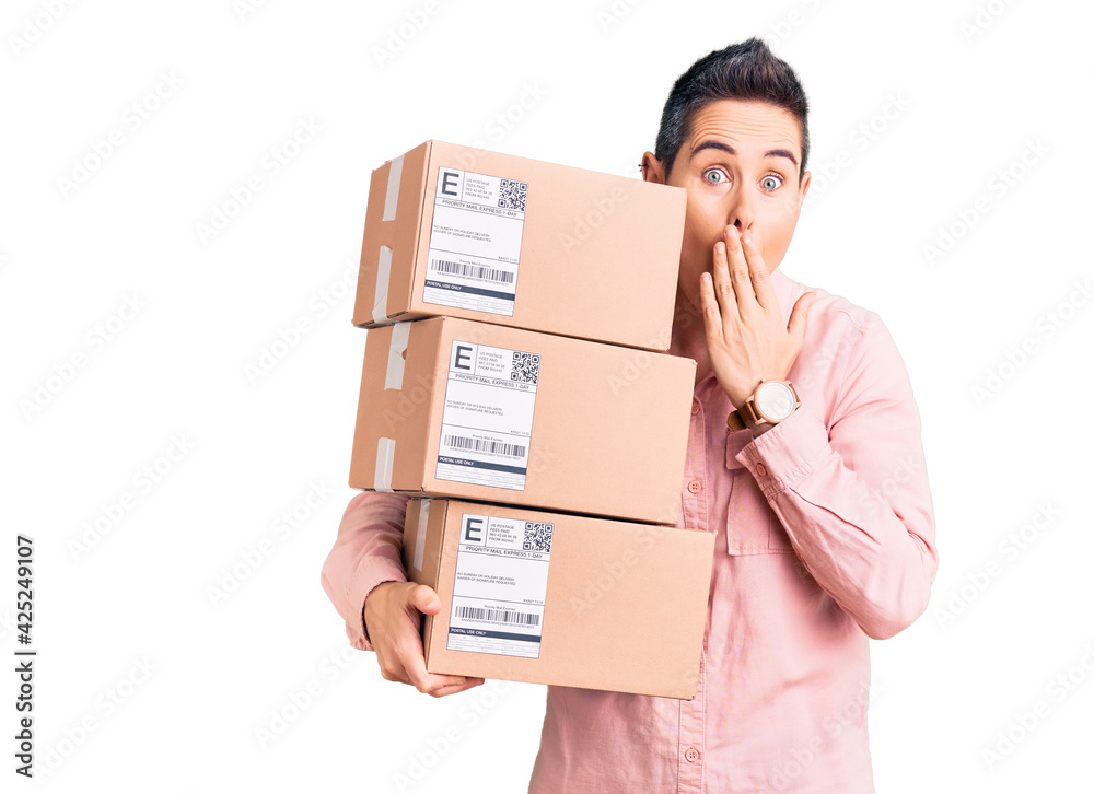 Young woman with short hair holding delivery package covering mouth with hand, shocked and afraid for mistake. surprised expression Young woman with short hair holding delivery package covering mouth with hand, shocked and afraid for mistake. surprised expression
