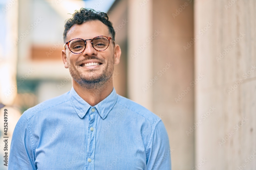 Young hispanic businessman smiling happy standing at the city.