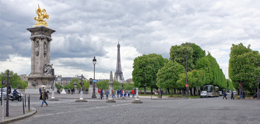  View of the Pont Alexandre lll. On the bridge are pedestrians and cars, the ship sails under the bridge