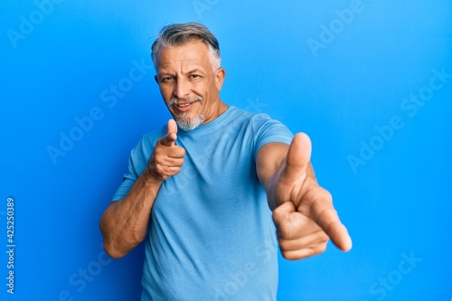 Middle age grey-haired man wearing casual clothes pointing fingers to camera with happy and funny face. good energy and vibes.