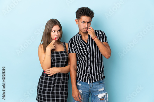 Teenager caucasian couple isolated on blue background having doubts while looking up