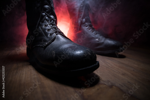 War concept. Old military shoe in a dark toned foggy background. Creative concept of conflict between countries, military aggression. © zef art