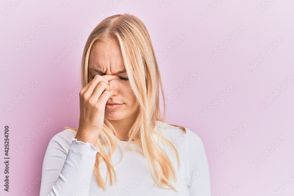 Young blonde girl wearing casual clothes tired rubbing nose and eyes feeling fatigue and headache. stress and frustration concept. Young blonde girl wearing casual clothes tired rubbing nose and eyes feeling fatigue and headache. stress and frustration concept.