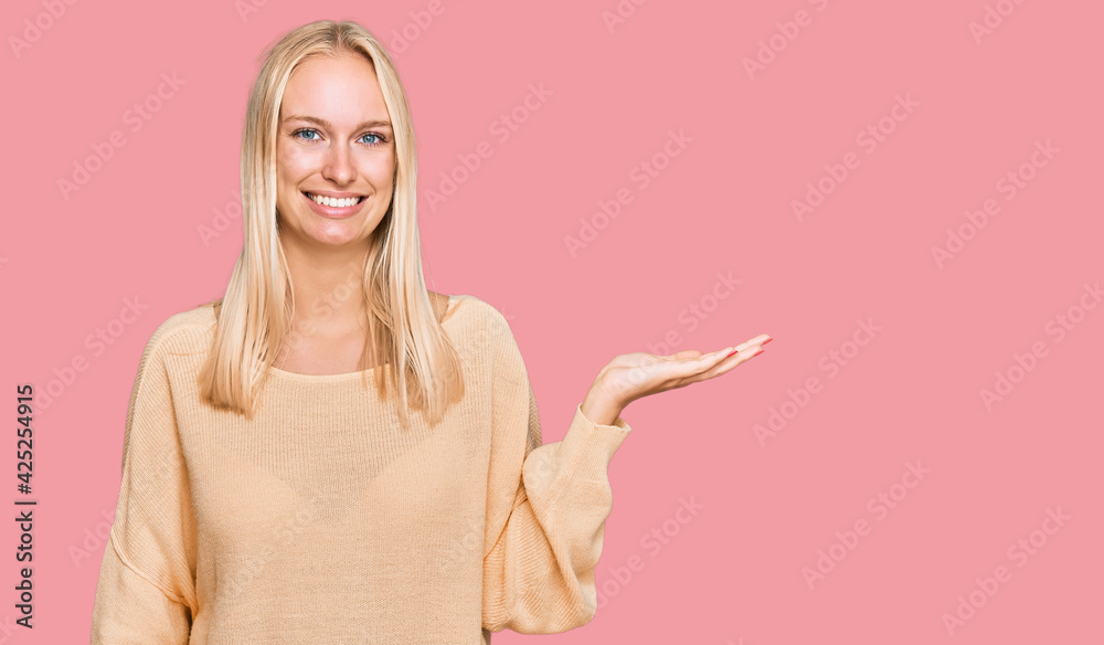 Young blonde girl wearing casual clothes smiling cheerful presenting and pointing with palm of hand looking at the camera. Young blonde girl wearing casual clothes smiling cheerful presenting and pointing with palm of hand looking at the camera.