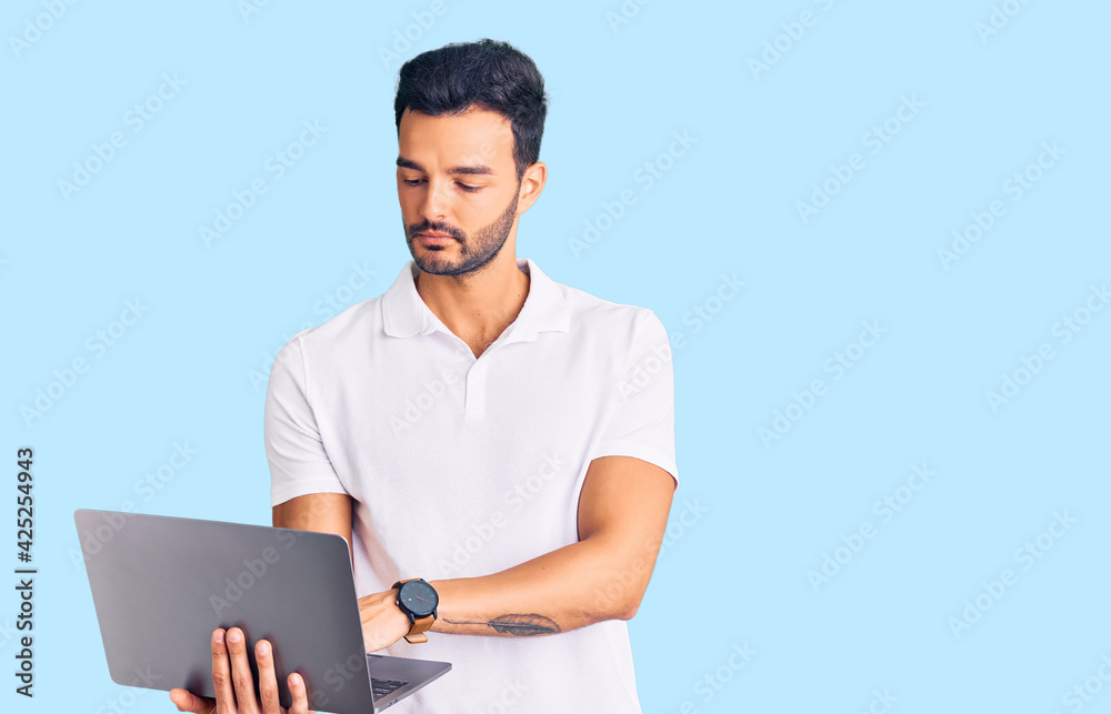 Young handsome hispanic man working using computer laptop thinking attitude and sober expression looking self confident