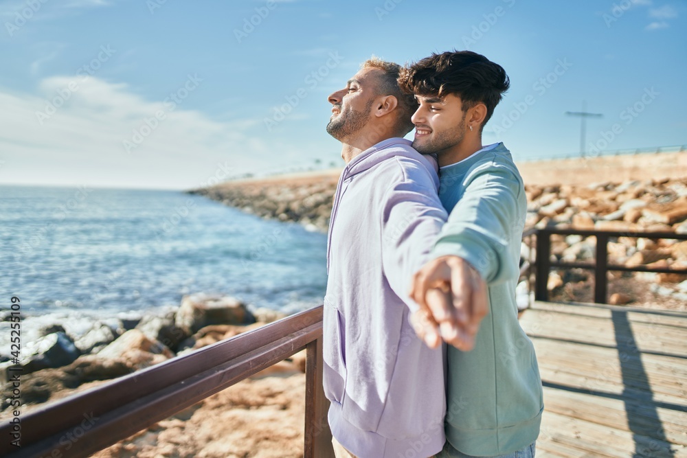 Young gay couple breathing with arms opened at the beach. Young gay couple breathing with arms opened at the beach.