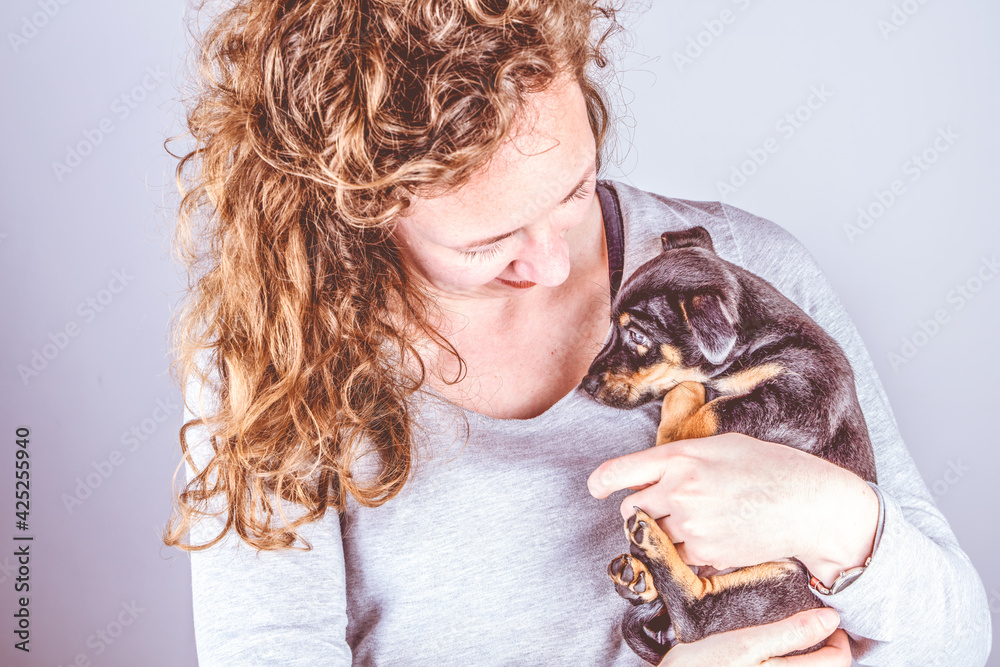 Part of a woman with brown curls, she lovingly cuddles a tiny Jack Russel Terrier puppy in her arms. In vintage, retro colors Part of a woman with brown curls, she lovingly cuddles a tiny Jack Russel Terrier puppy in her arms. In vintage, retro colors