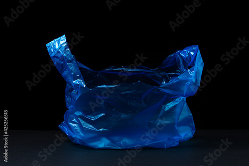 Plastic blue bag on a black background. Transparent blue package on a dark background.