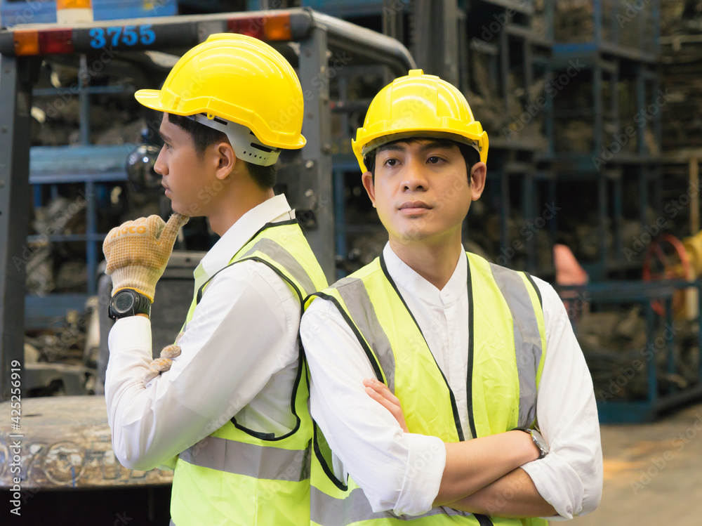 Men work together, Asian engineer worker men stand, crossed arms, and catch chin in factory-warehouse Men work together, Asian engineer worker men stand, crossed arms, and catch chin in factory-warehouse
