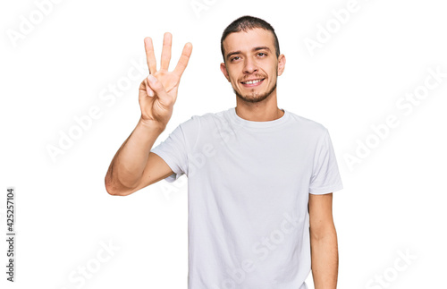 Hispanic young man wearing casual white t shirt showing and pointing up with fingers number three while smiling confident and happy.