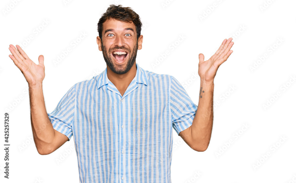 Handsome young man with beard wearing casual fresh shirt celebrating crazy and amazed for success with arms raised and open eyes screaming excited. winner concept Handsome young man with beard wearing casual fresh shirt celebrating crazy and amazed for success with arms raised and open eyes screaming excited. winner concept