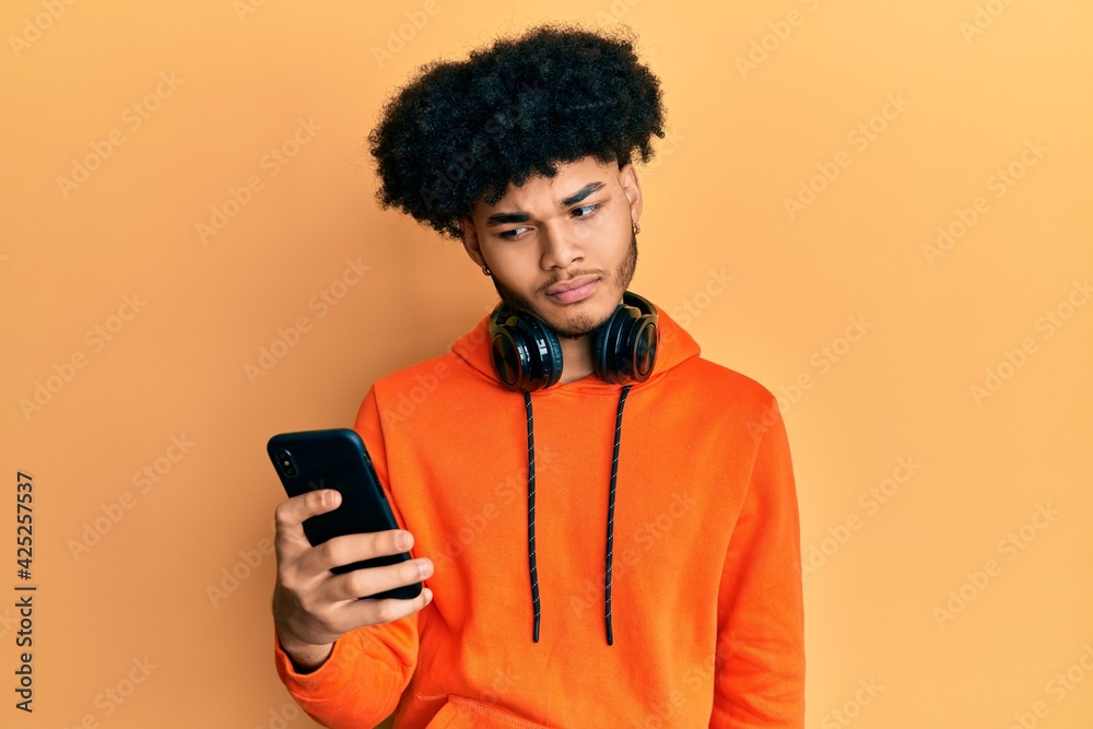 Young african american man with afro hair using smartphone skeptic and nervous, frowning upset because of problem. negative person. Young african american man with afro hair using smartphone skeptic and nervous, frowning upset because of problem. negative person.