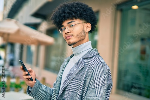 Young african american businessman with serious expression using smartphone at the city.