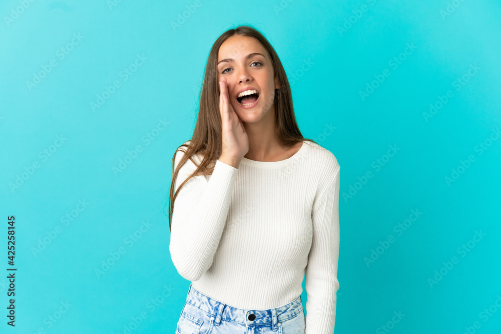 Young woman over isolated blue background shouting with mouth wide open